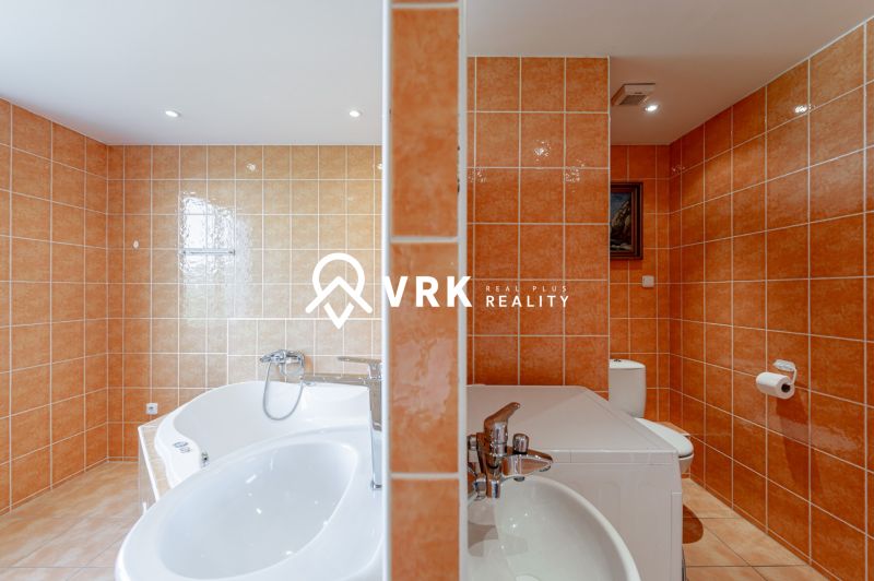 Bathroom in a 2-room apartment with a barrel-shaped bathtub, sink, and orange tiles.