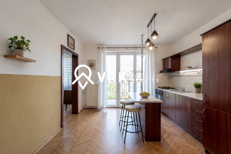 A kitchen in a 2-room apartment with a bar counter and a wooden decor floor.