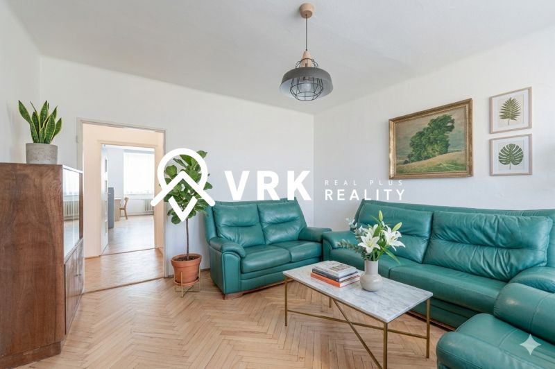 Living room in a two-room apartment with leather sofas and a table, wooden decor flooring.