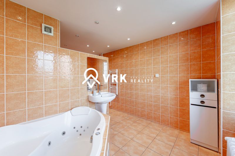 A bathroom in a 2-room apartment with a hot tub and beige tiles.