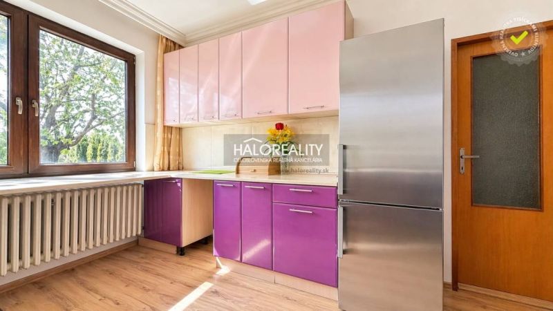 A kitchen in a family house with a colorful cabinet, a stainless steel refrigerator, and a floor with a wooden decor.