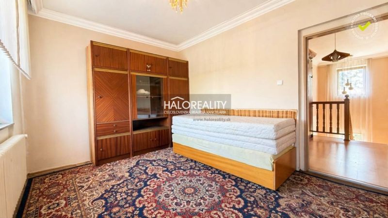 A room with a carpet and furniture in a family house, the door leads to the hallway.