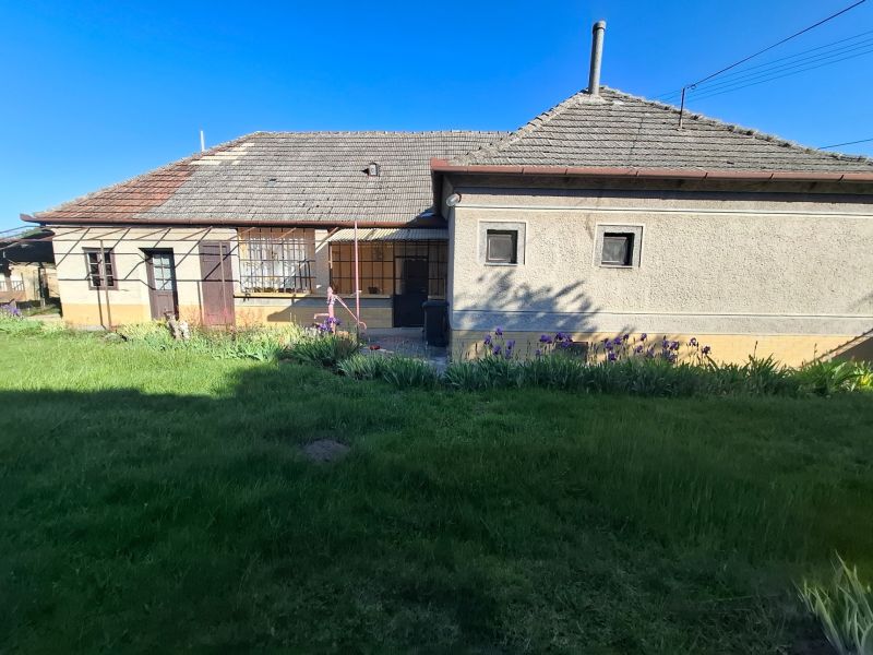 A family house in Tvrdošovce with a lawn and a flower bed in front of the building.