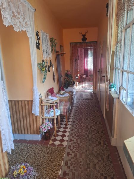 A narrow corridor with carpet, wooden decor, and curtains in a family house.
