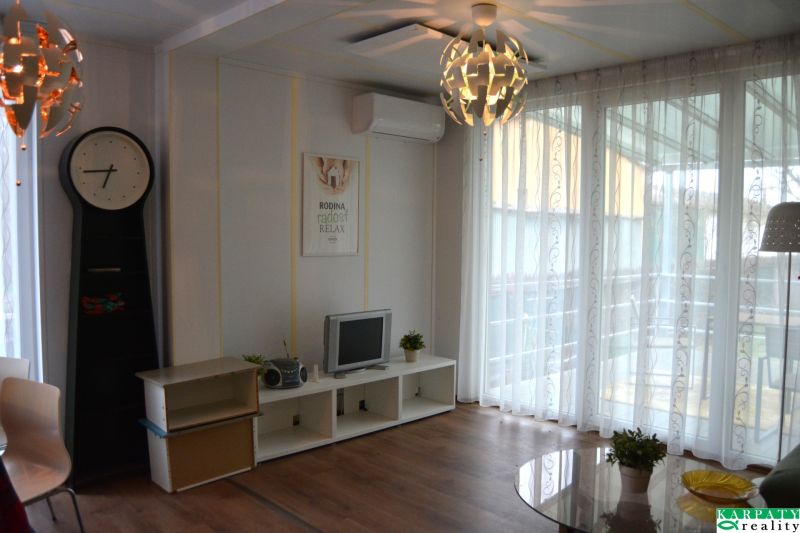 Living room in a family house with a TV, clock, and wooden decor flooring.