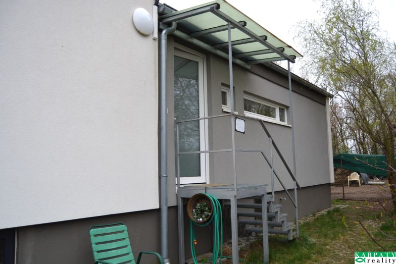 A family house on Húšky Street in Borský Svätý Jur with a metal staircase and a shelter.