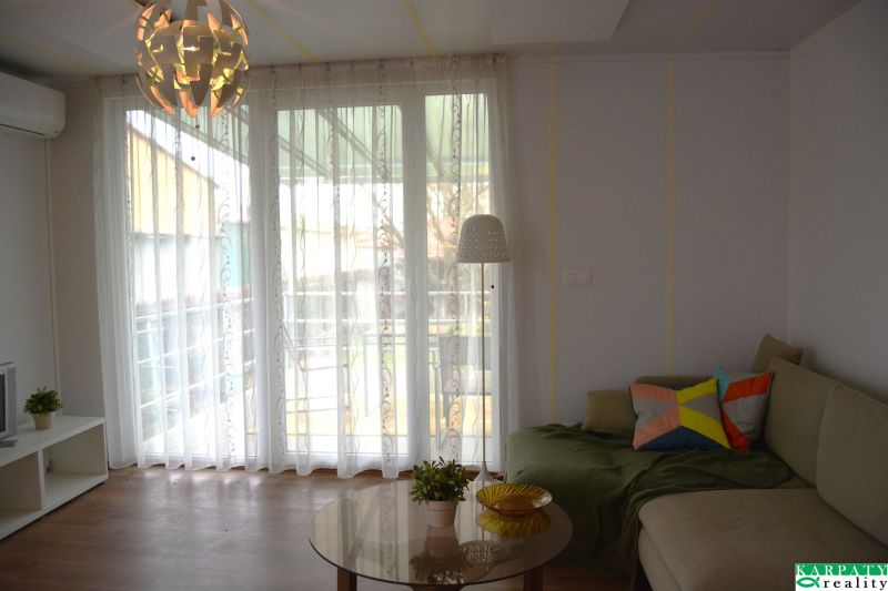Living room in a family house with a sofa, wooden decor flooring, and a glass wall.