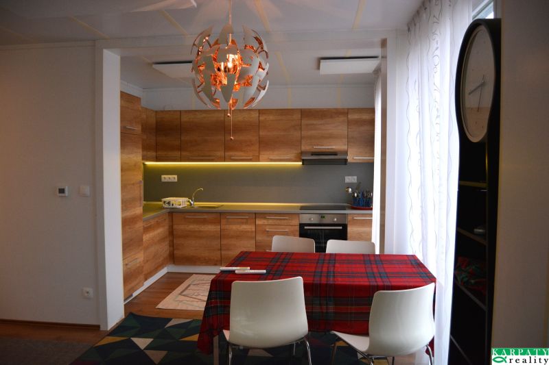 A kitchen with a wood-patterned floor, a table, and decorative lighting in a family house.