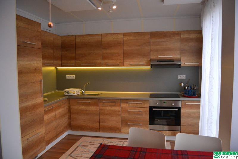 A kitchen in a family house with wooden decor and recessed lighting above the countertop.