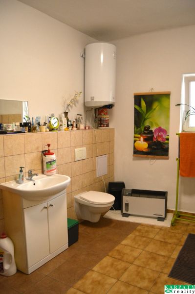 Bathroom with a sink, wall-mounted toilet, water heater, and decorative curtain.