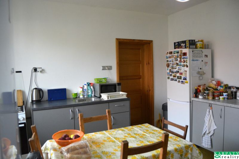 A kitchen in a family house with a dining table, refrigerator, and kitchen unit.