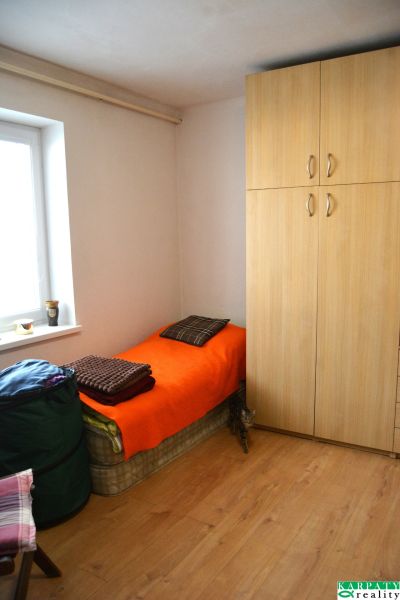 A room in a family house with a bed, a wardrobe, and a floor with a wooden decor.