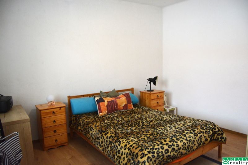 Bedroom in a family house with a bed, nightstands, and a wooden decor floor.