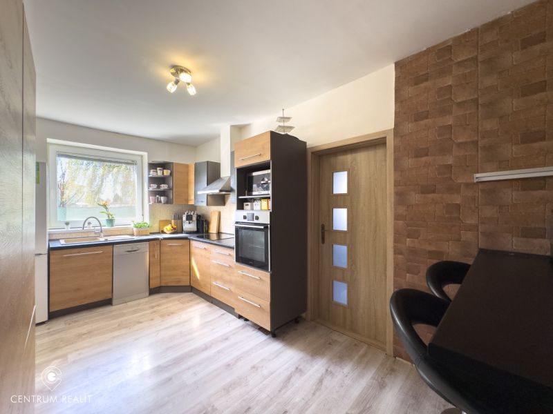 A kitchen in a family house with a wooden decor floor and brick cladding.