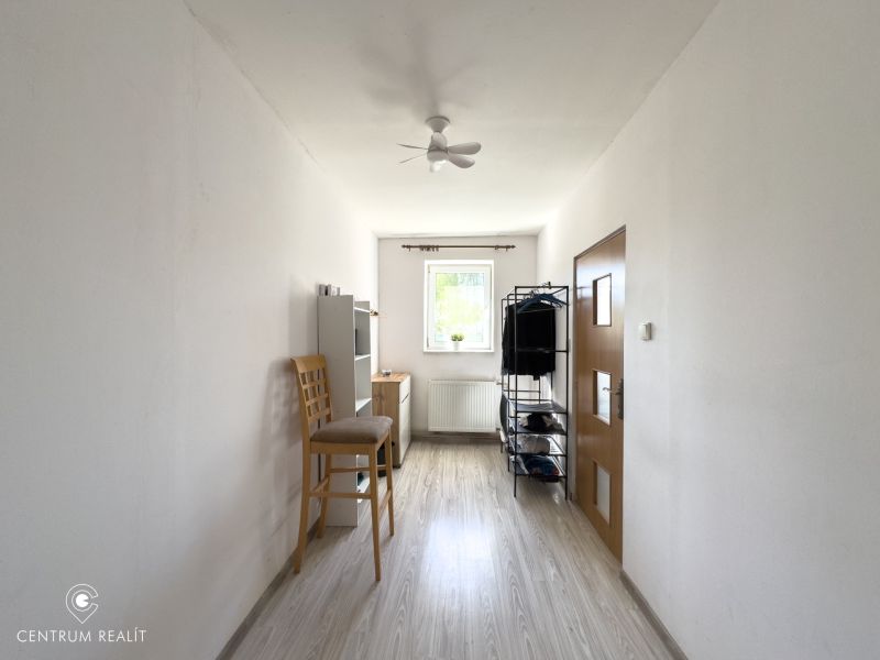 A narrow room with a window and a wooden decor floor in a family house.
