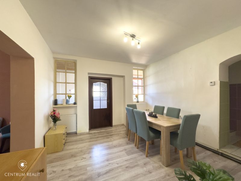Dining area with wood-patterned flooring and a bench at the table in a family house.