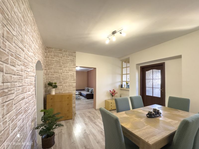 A dining room in a family house with a wooden decor floor and a stone wall.