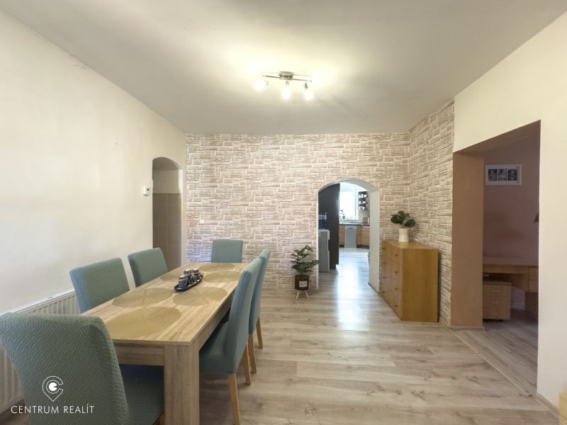 The dining room of a family house with a wooden decor floor and brick wallpaper.