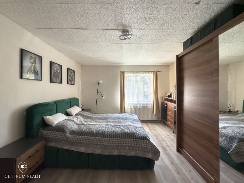 A bedroom in a family house with a large bed and a floor with a wooden decor.