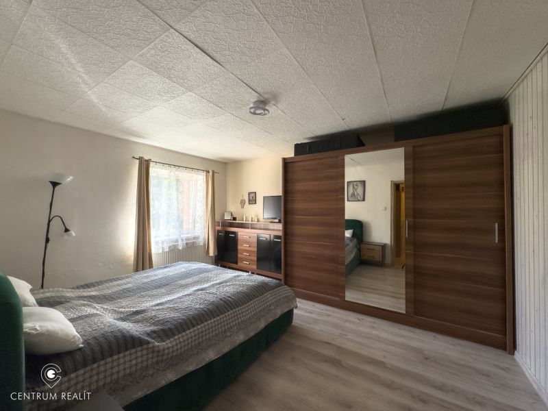 A bedroom in a family house with a bed, a wardrobe, and a floor with a wooden decor.
