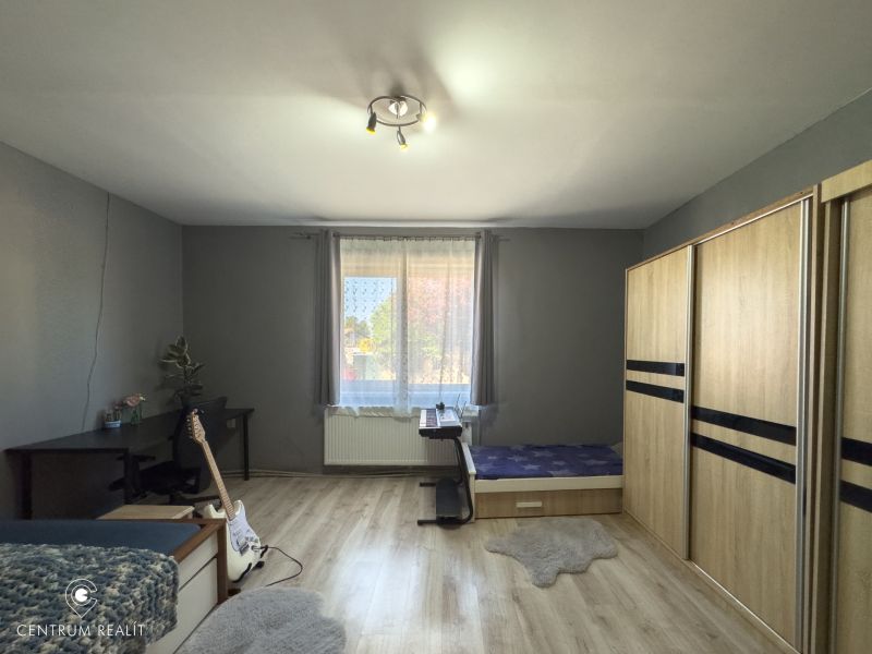 Bedroom with a large wardrobe, a desk, and a wooden decor floor in a family house.