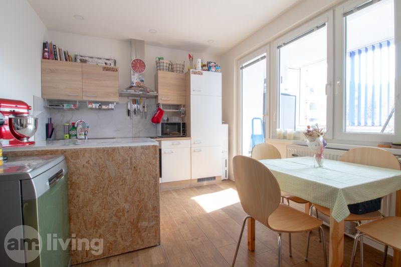 A kitchen in a 2-room apartment with a table and a wooden decor floor.