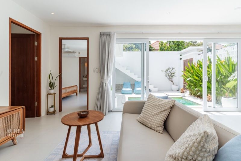 A bright living room in a villa with a view of the outdoor terrace through glass doors.