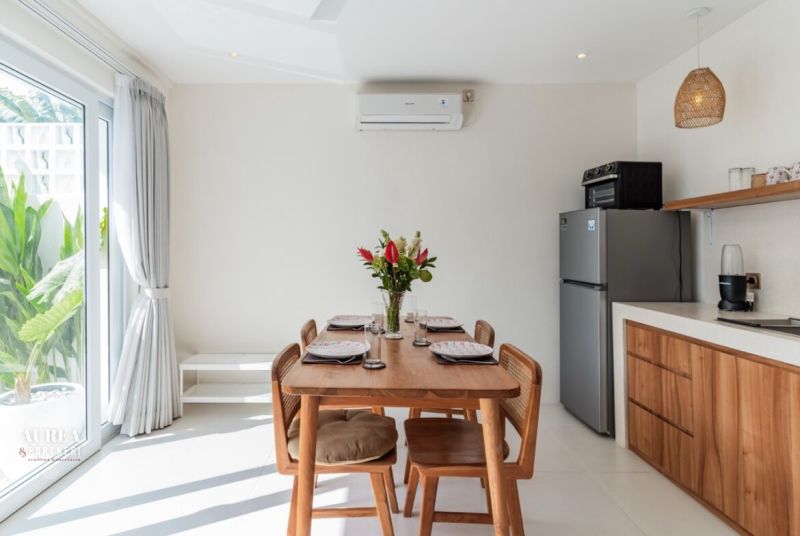 Dining room in a villa with wooden decor, kitchen unit, and dining table.