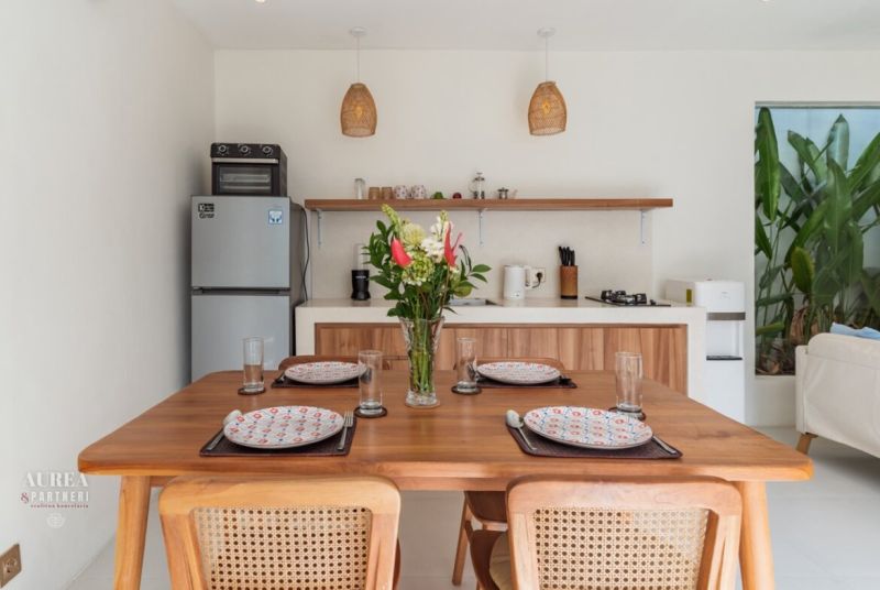 A bright kitchen in a villa with wooden decor and a dining table with flowers.
