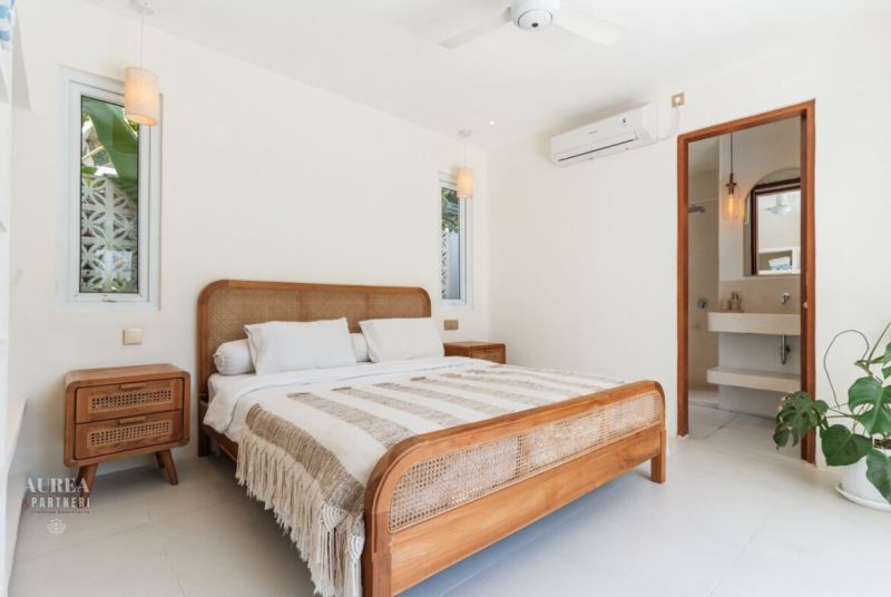 Bright bedroom in a villa with wooden furniture and a striped blanket.