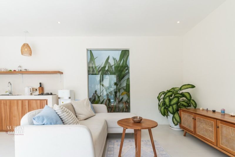 Living room in a villa with a white sofa, wooden coffee table, and a houseplant.