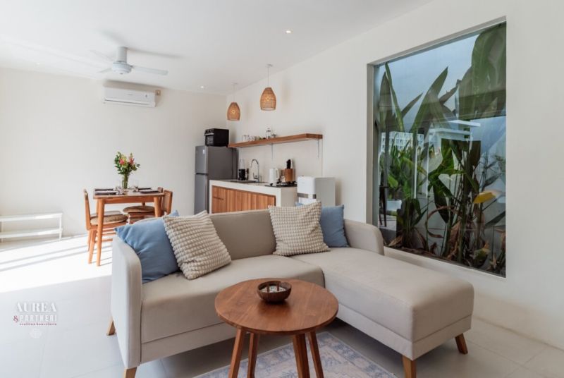 Living room in a villa with a comfortable sofa, dining table, and kitchen unit.