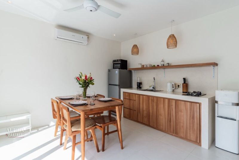 A kitchen in a villa with wooden decor, a table, flowers, and a ceiling fan.