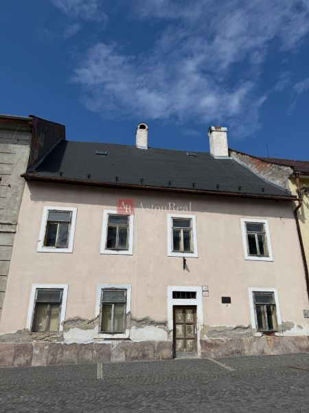 A family house in Kremnica with a worn facade and a stone plinth section.