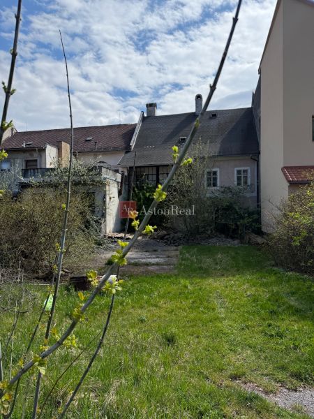 A family house in Kremnica with a spacious garden, shrubs, and newly growing greenery.