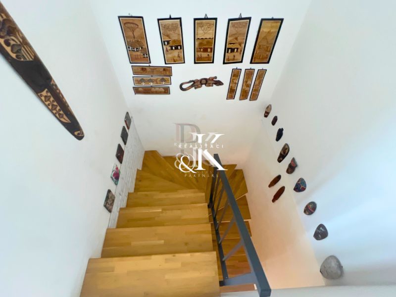 A staircase with a wooden decor floor and African masks in a family house.