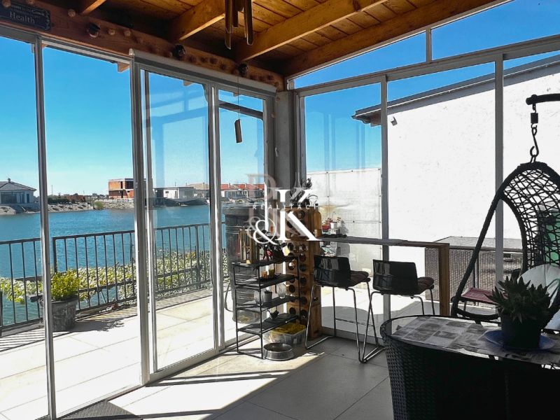 A glazed terrace with a view of the lake and seating in a family house.
