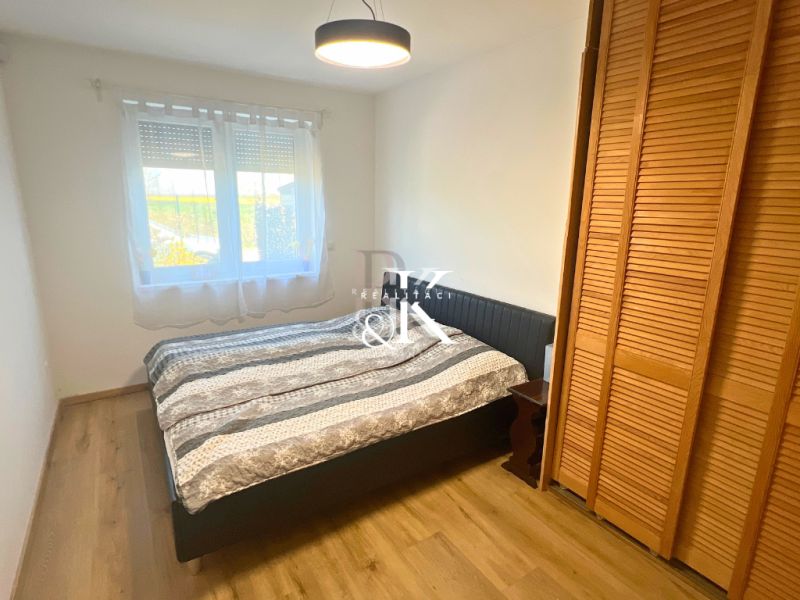 Bedroom in a family house with a bed, wardrobe, and wooden decor flooring.