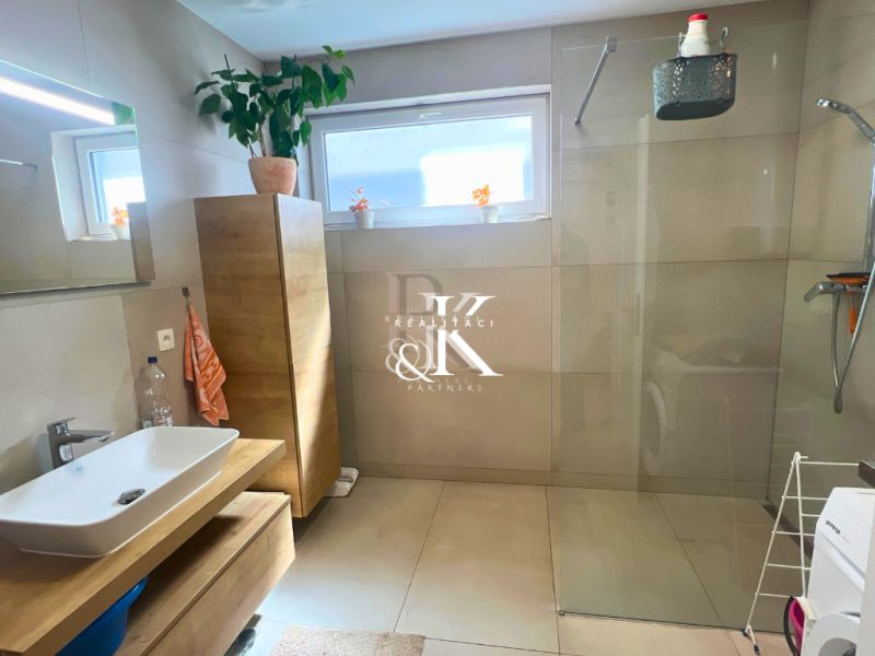 A bathroom in a family house with a bathtub, a sink, and a cabinet with a wood decor.