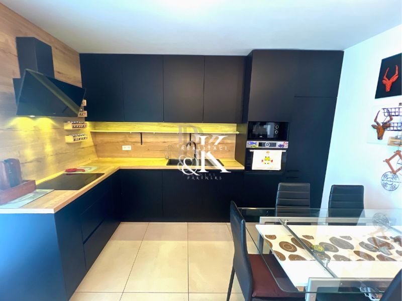 A kitchen in a family house with black furniture and a wooden decor floor.