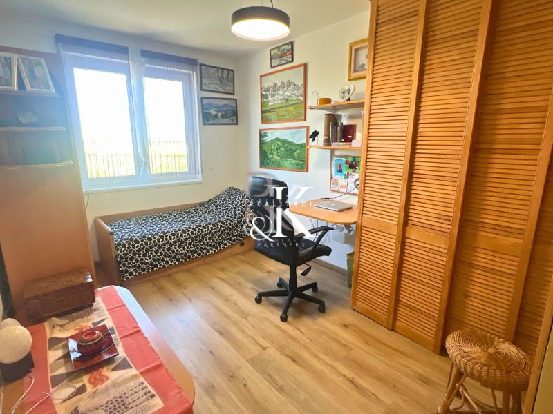 A room in a family house with one bed, a desk, and a floor with a wooden decor.