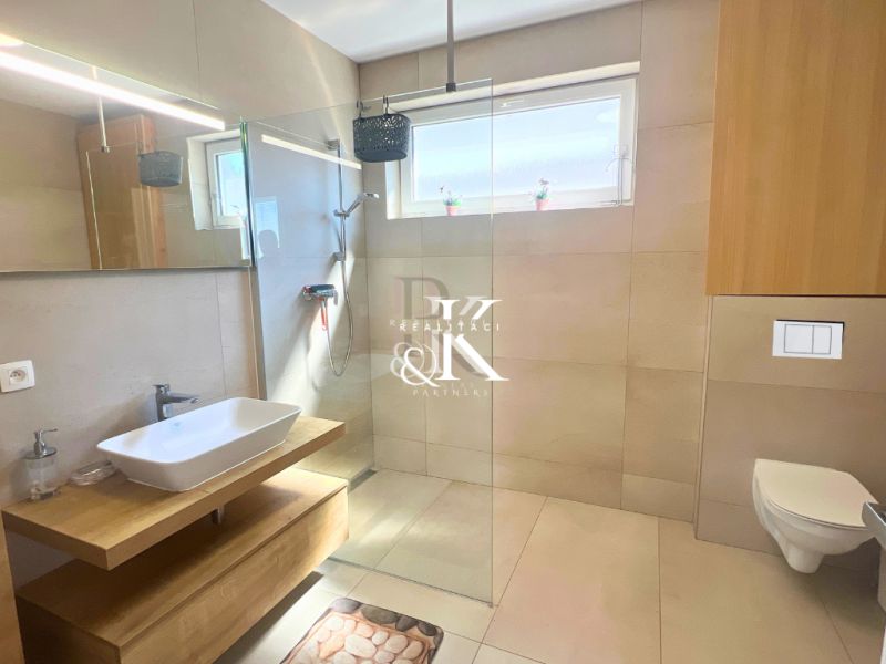 A bathroom in a family house with a minimalist shower and a sink on a wooden cabinet.
