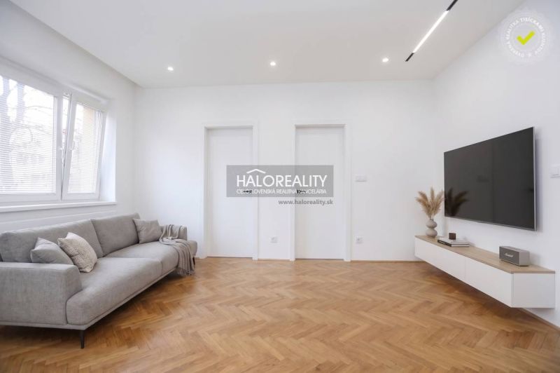 Living room in a 3-room apartment with a wood-patterned floor and a TV on the wall.