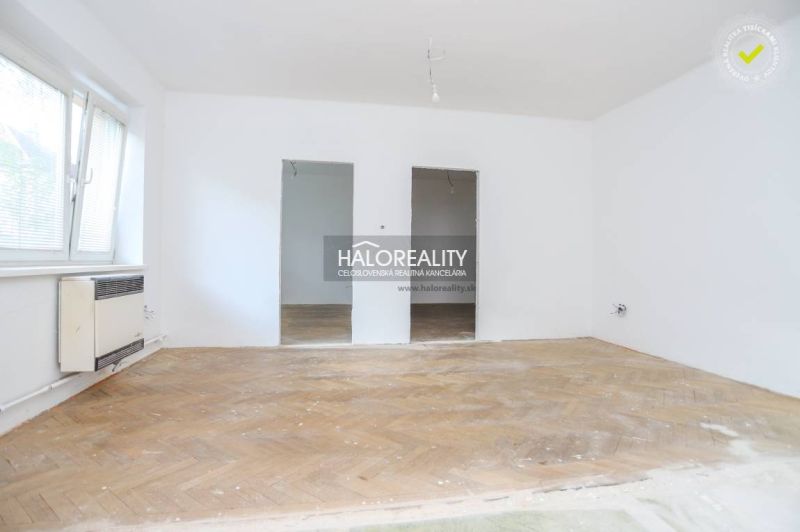 A spacious room in a 3-room apartment with a wooden decor floor, white walls, and a window.