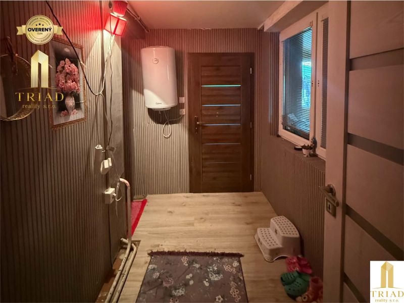 A hallway in a family house with a wooden decor floor, doors, and a water heater.