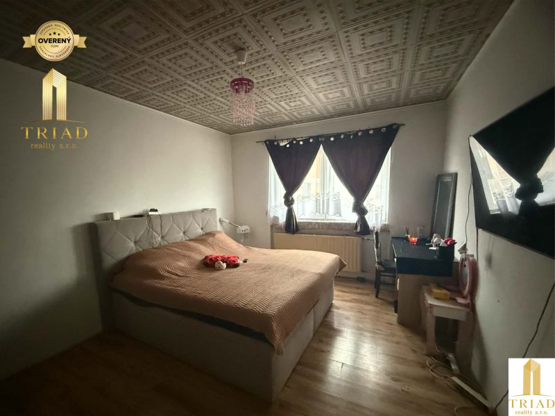 A bedroom in a family house with a wooden decor floor, a bed, and a table.