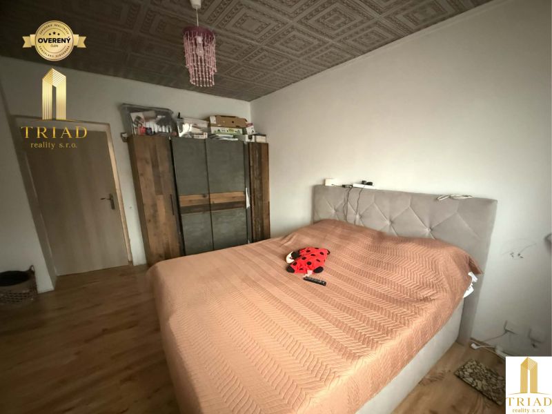 Bedroom in a family house with a bed, wardrobe, and wooden decor flooring.