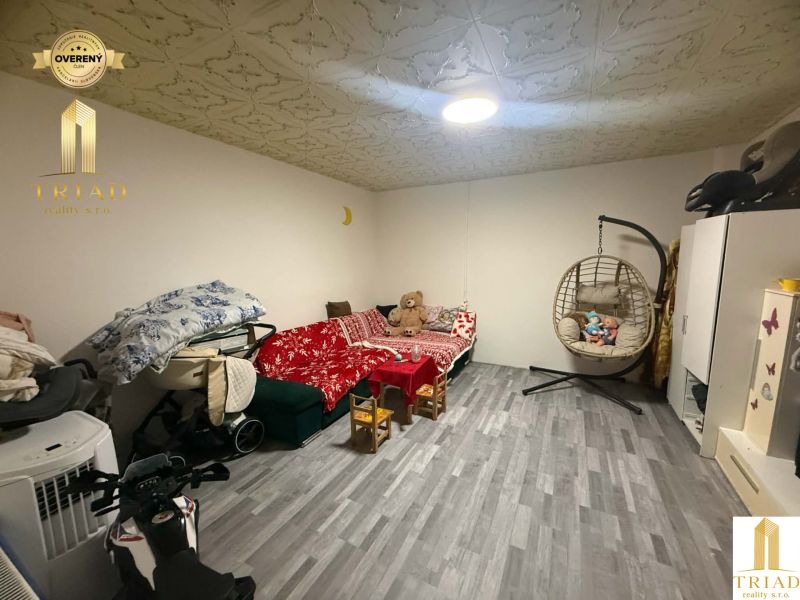 A children's room in a family house with a sofa, a rocking chair, and a floor with a wooden decor.