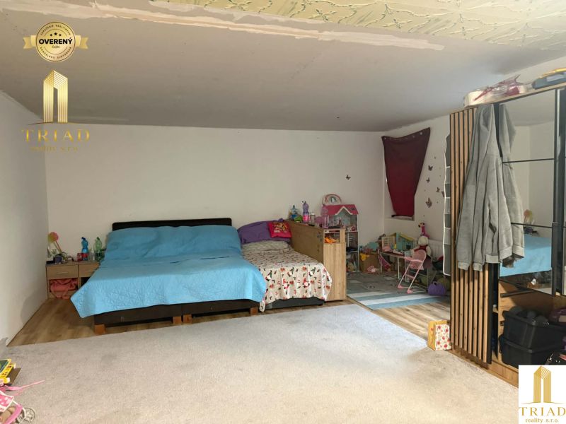 A room in a family house with a wooden decor floor, children's toys, and a bed.
