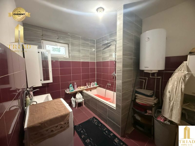 A bathroom in a family house with a bathtub, sink, washing machine, and water heater.